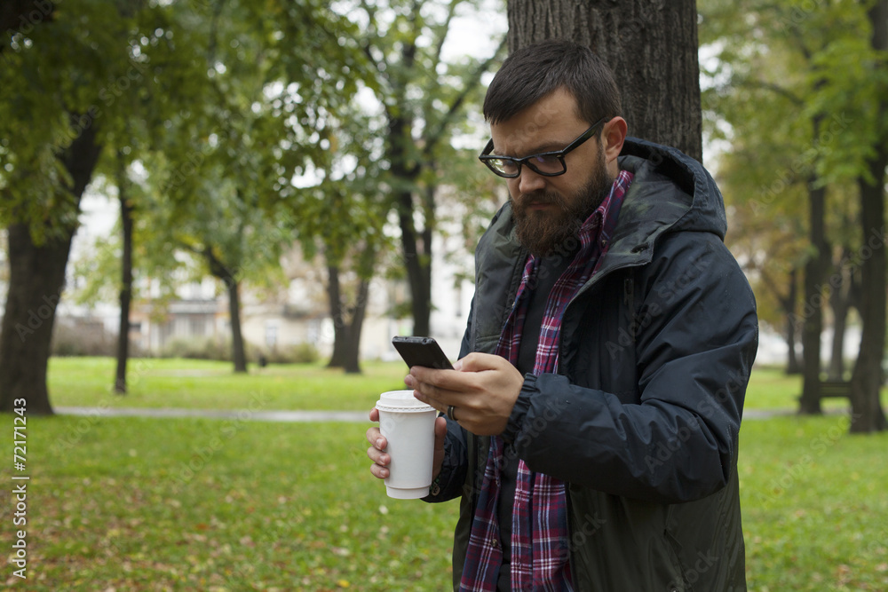 Man With Beard And Glasses Holding Phone and To Go Cup Man With Beard And Glasses Holding Phone and To Go Cup