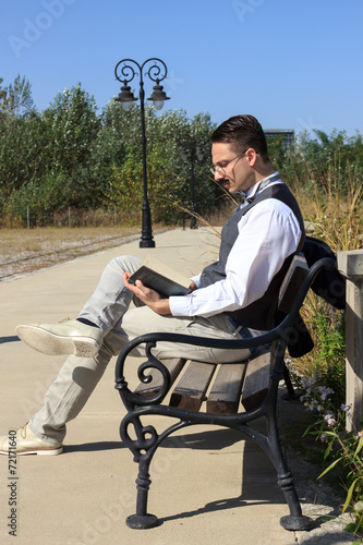 Pensive man with mustache sitting on bench reading book