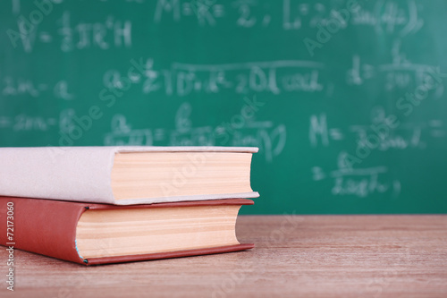 Books on wooden table on blackboard background