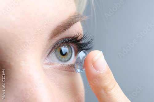 Medicine and vision concept - young woman with contact lens,