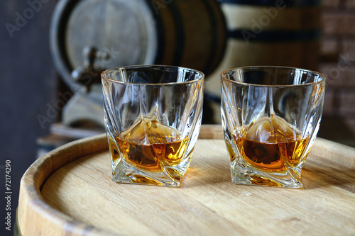 Glasses of brandy in cellar with old barrels