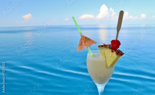 A tropical drink on a cruise ship rail with ocean in the backgro
