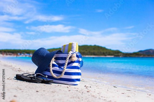 Blue bag, straw hat, flip flops and towel on white tropical