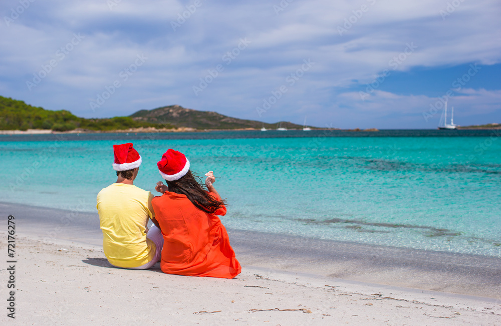 Young romantic couple in Santa hats during beach vacation Young romantic couple in Santa hats during beach vacation