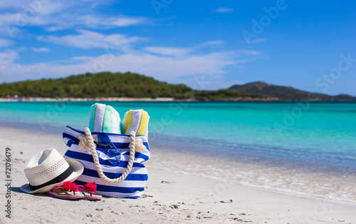 Stripe bag, straw hat, sunblock and frisbee on white sandy
