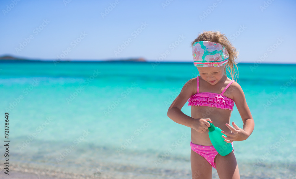 Little adorable girl in swimsuit with suntan lotion bottle Little adorable girl in swimsuit with suntan lotion bottle