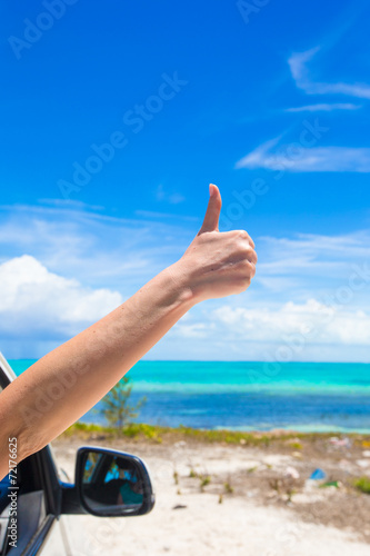 Female hand showing thumbs up on the beach