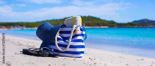 Blue bag, straw hat, flip flops and towel on white tropical