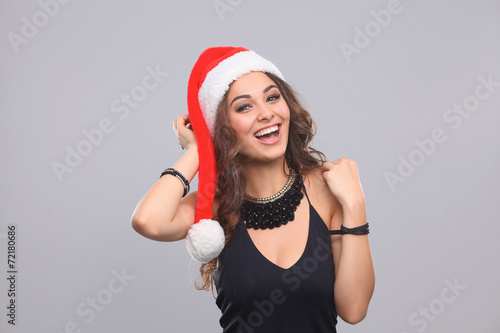 Attractive smiling woman in Santa Cap. Isolated over a gray