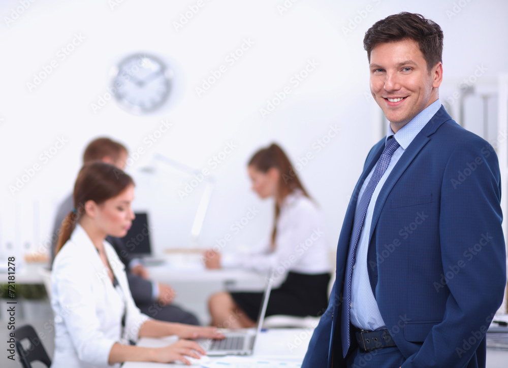 Obraz premium Successful business man standing with his staff in background at