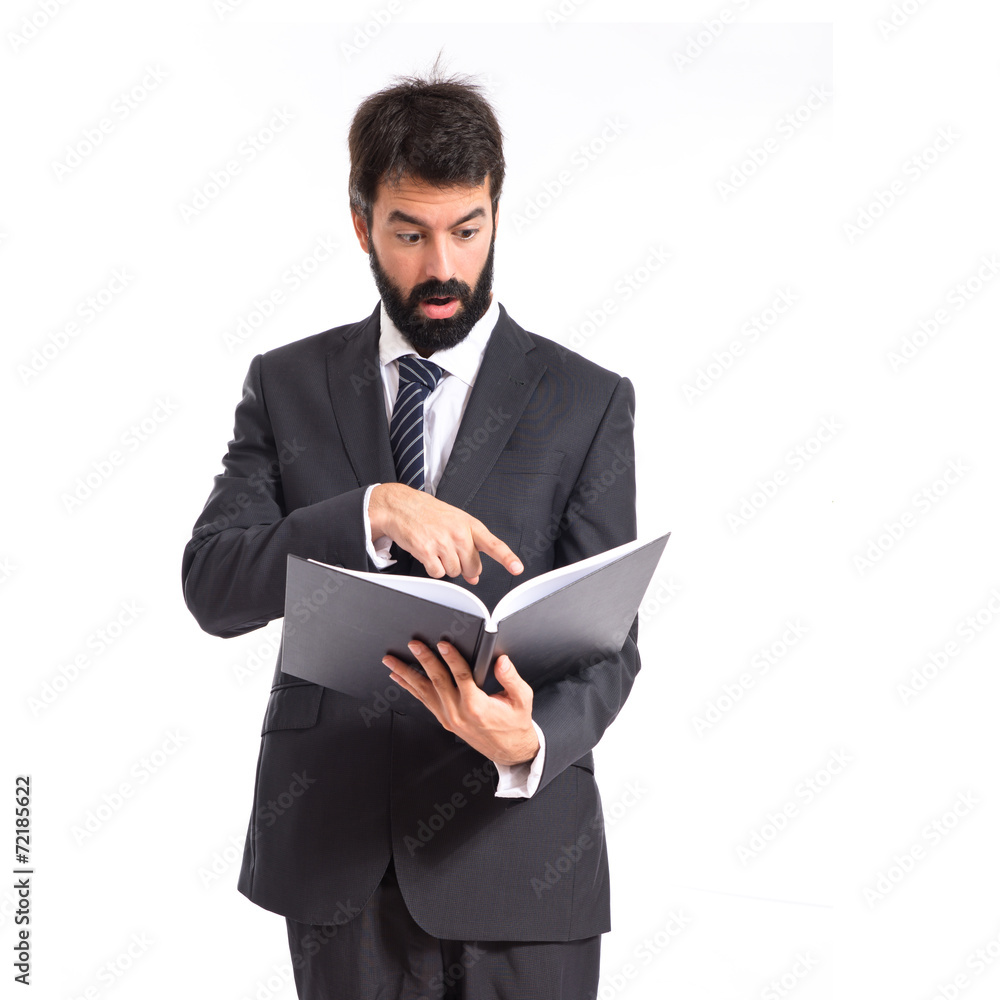 Surprised businessman reading a book over white background Surprised businessman reading a book over white background