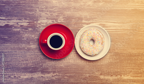 Cup of coffee and donut on a table.
