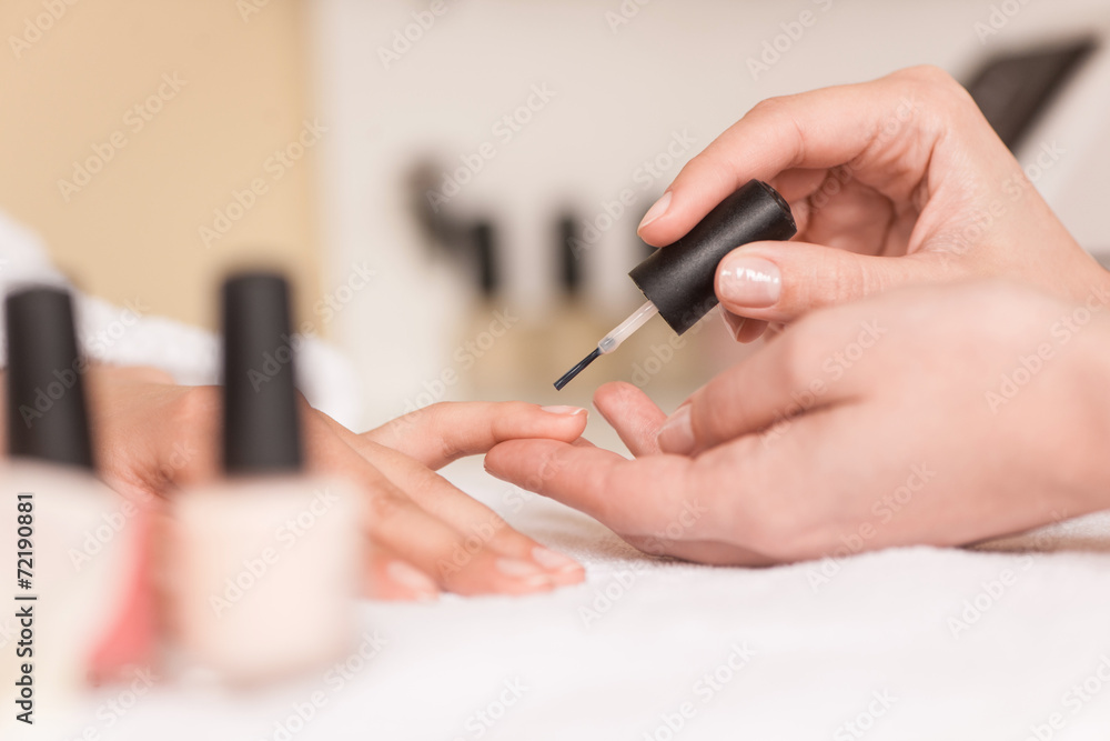 Woman in nail salon receiving manicure by beautician. Woman in nail salon receiving manicure by beautician.