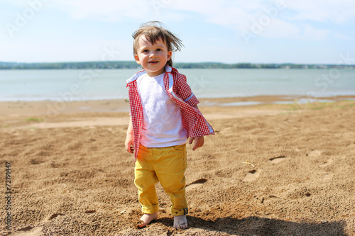 happy barefoot baby walking on riverside