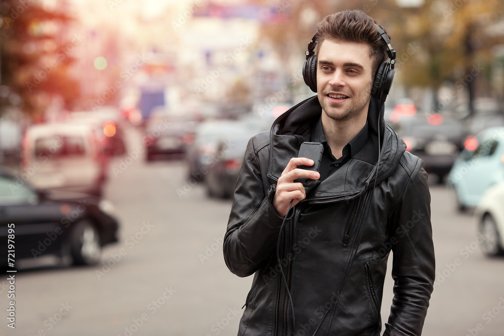 man in headphones on the street. Standing with phone in hand man in headphones on the street. Standing with phone in hand