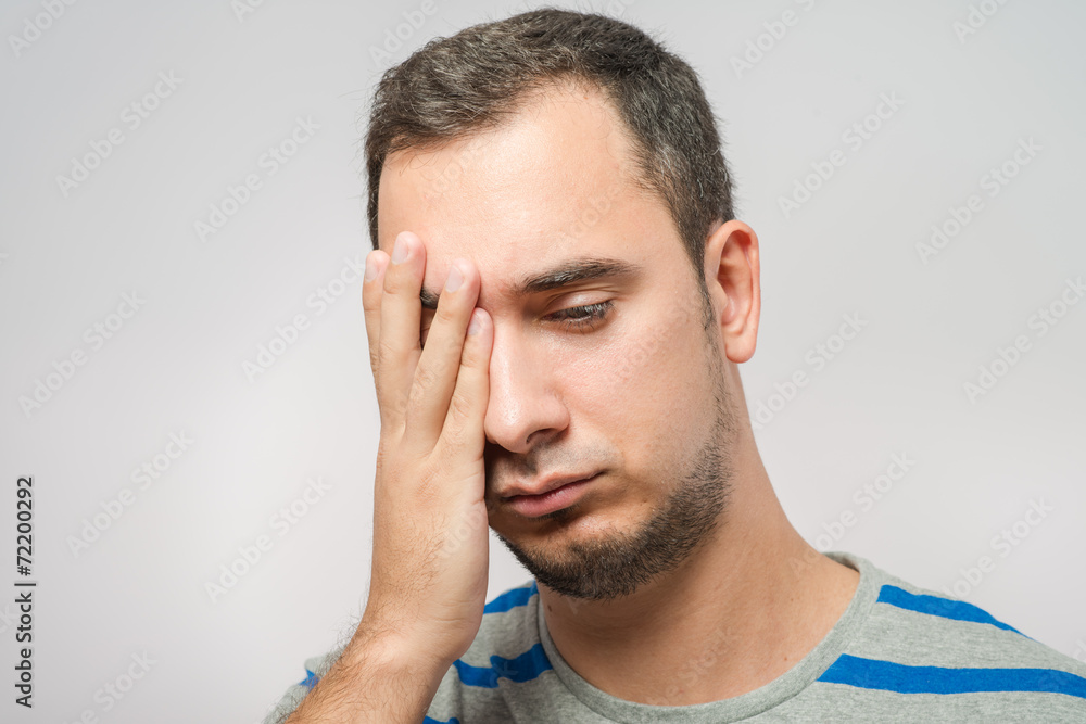 Obraz premium Desperate young man covering with his head in his hands