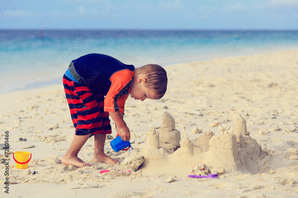little boy building sand castle on beach little boy building sand castle on beach