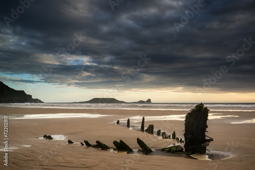 Landscape image of old shipwreck on beach at sunset in Summer