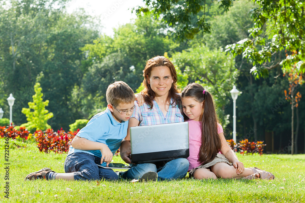 Happy Family using laptop lying on grass Happy Family using laptop lying on grass