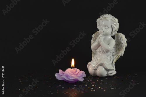 Angel statue object with lit candle isolated on black background 