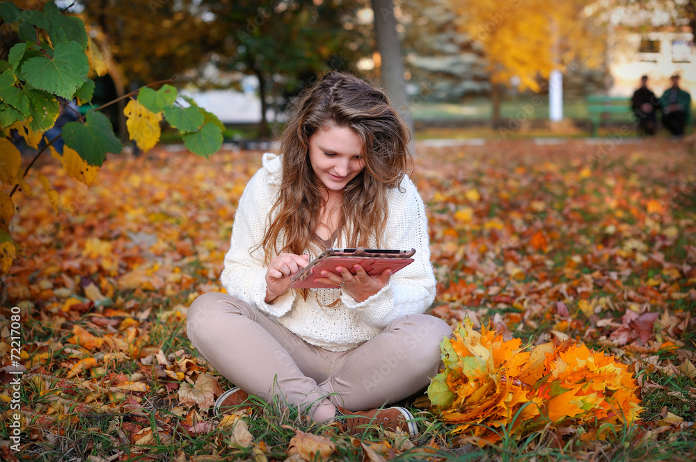 beautiful girl in autumn park with a tablet resting beautiful girl in autumn park with a tablet resting