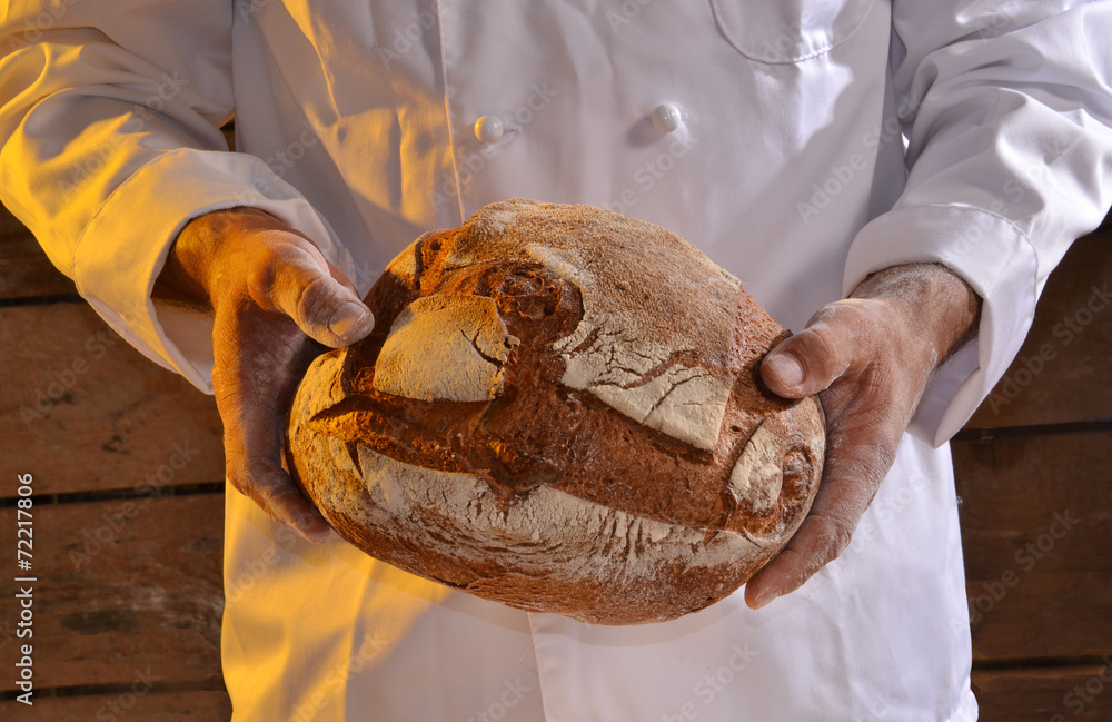 Panadero sujetando un pan recién horneado.