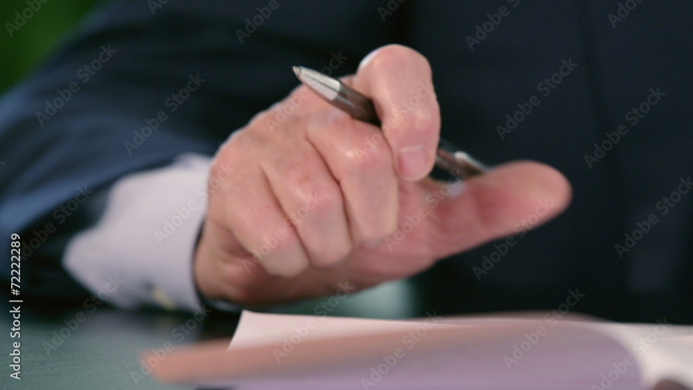 Hand of a business man signing documents with pen Hand of a business man signing documents with pen