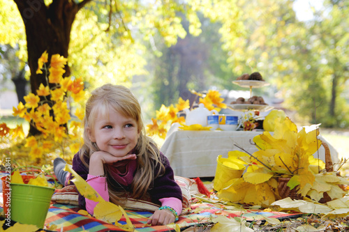 Little girl having picnic under autumn trees