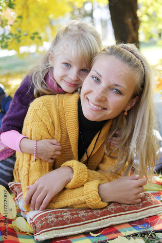 Mother and daughter lying under autumn tree