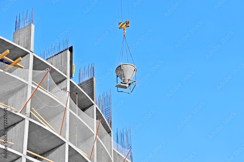 Crane lifting concrete mixer container against blue sky Crane lifting concrete mixer container against blue sky