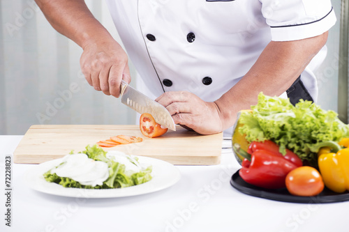 Chef's hands cutting Tomato