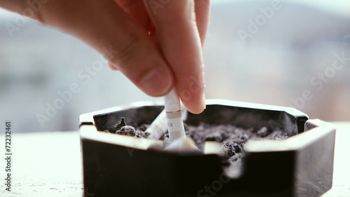 Hand putting off a cigarette in ashtray