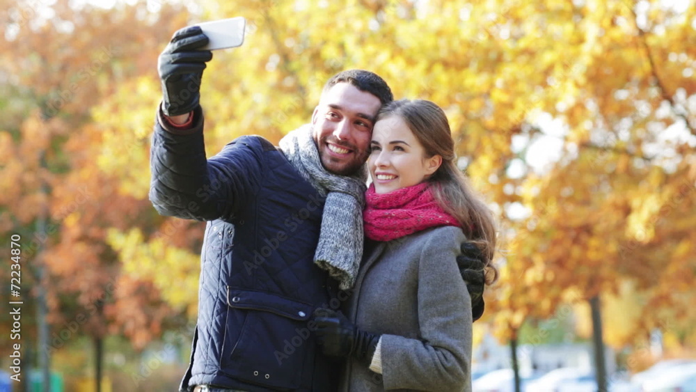 smiling couple with smartphone in autumn park smiling couple with smartphone in autumn park