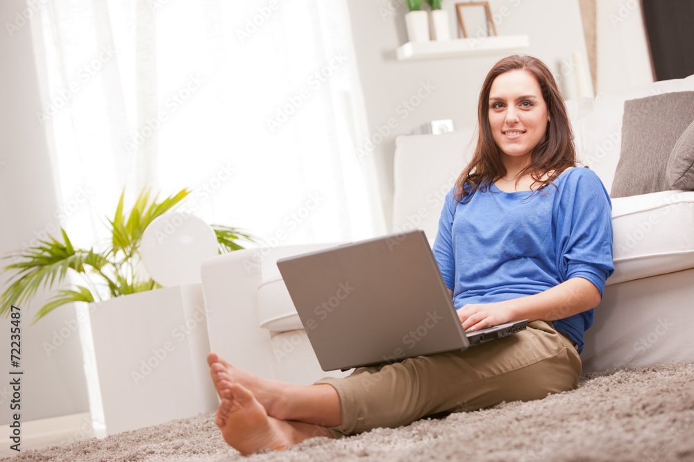young woman using her notebook in a living room young woman using her notebook in a living room