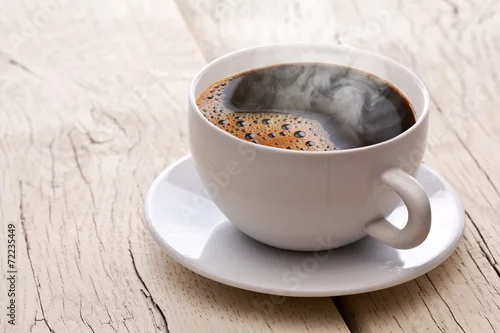 Obraz Cup of hot coffee on an old wooden table.