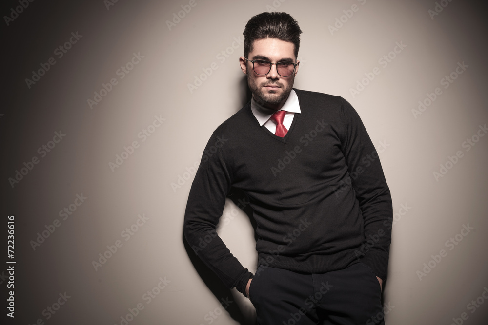 Obraz premium Handsome business man leaning on a grey wall