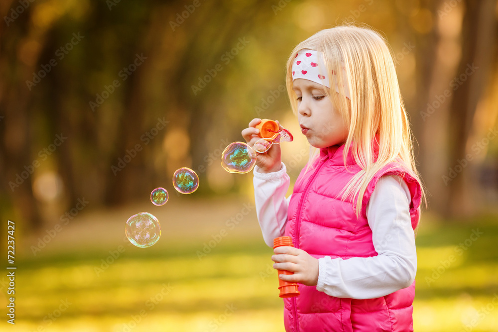 Beautiful girl blowing soap bubbles in the park