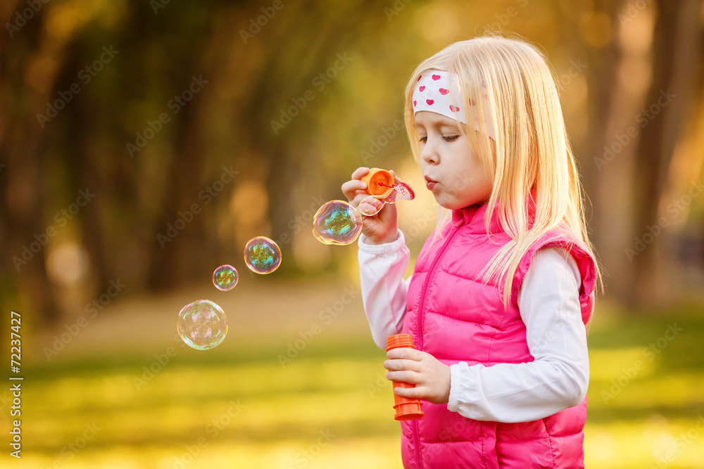 Beautiful girl blowing soap bubbles in the park Beautiful girl blowing soap bubbles in the park