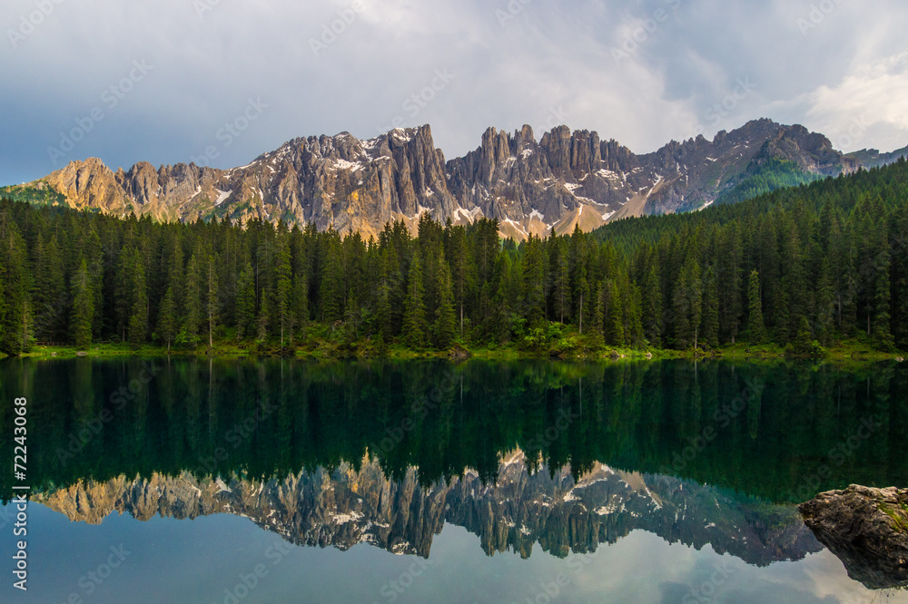 Latemar mountain and woods reflected in lake Carezza, Dolomites