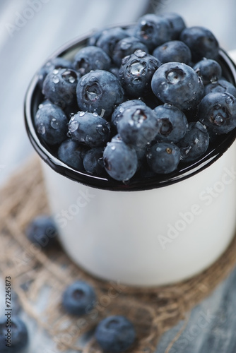 Close-up of an enameled cup with ripe blueberries, vertical shot