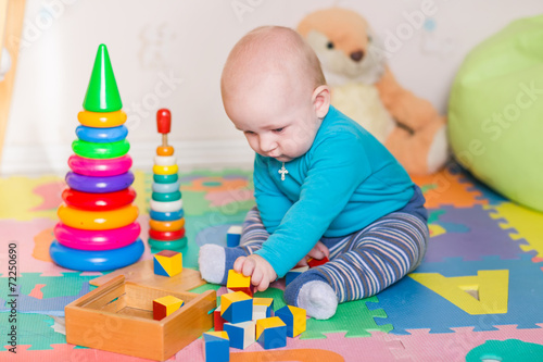 Cute little baby playing with colorful toys indoors
