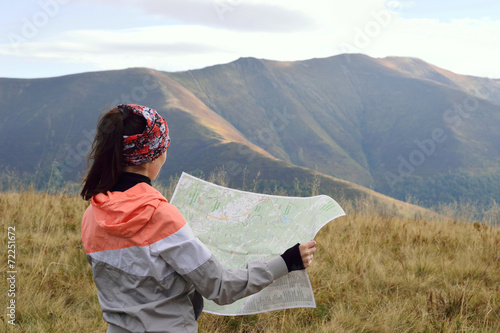 Girl tourist looking on a map in the mountains