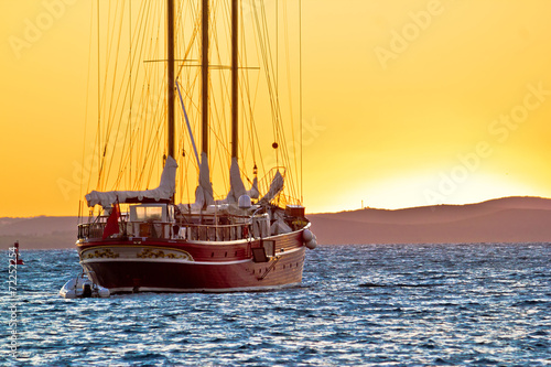 Old wooden sailboat at golden sunset