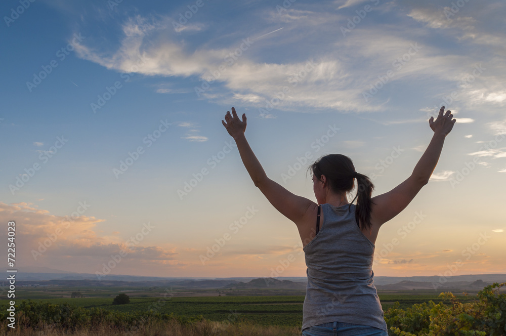 Young woman, hands up, sowing happiness at sunset Young woman, hands up, sowing happiness at sunset