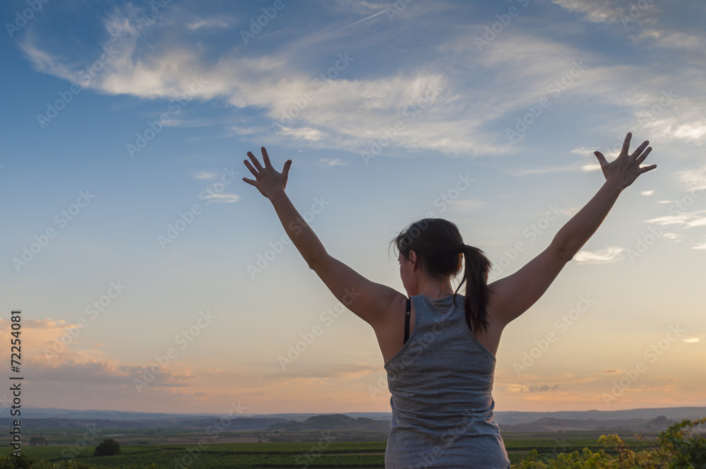 Young woman, hands up, sowing happiness at sunset Young woman, hands up, sowing happiness at sunset
