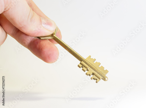 Obraz na płótnie Golden key in fingers on white background w salonie