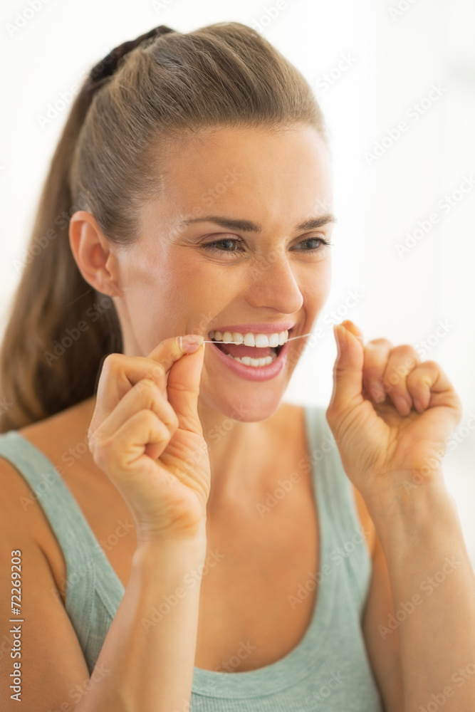 Fototapeta premium Portrait of young woman using dental floss