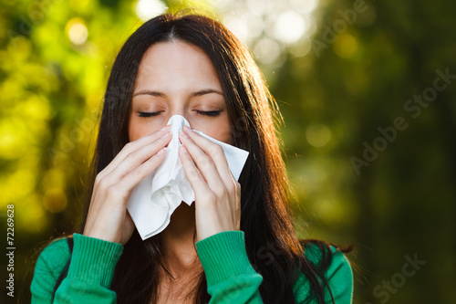 Woman blowing nose in nature
