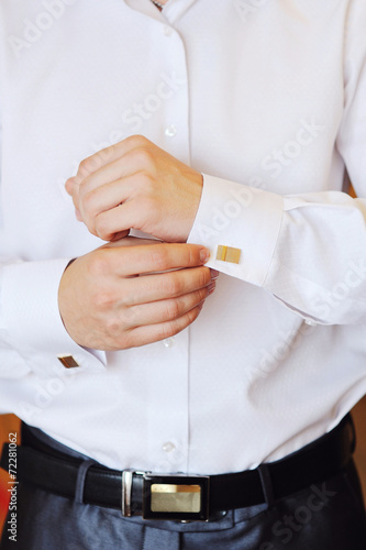 man puts cufflinks on sleeve white shirts