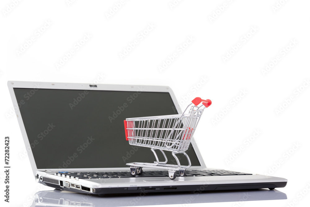 Shopping cart over a laptop computer, isolated on white backgrou